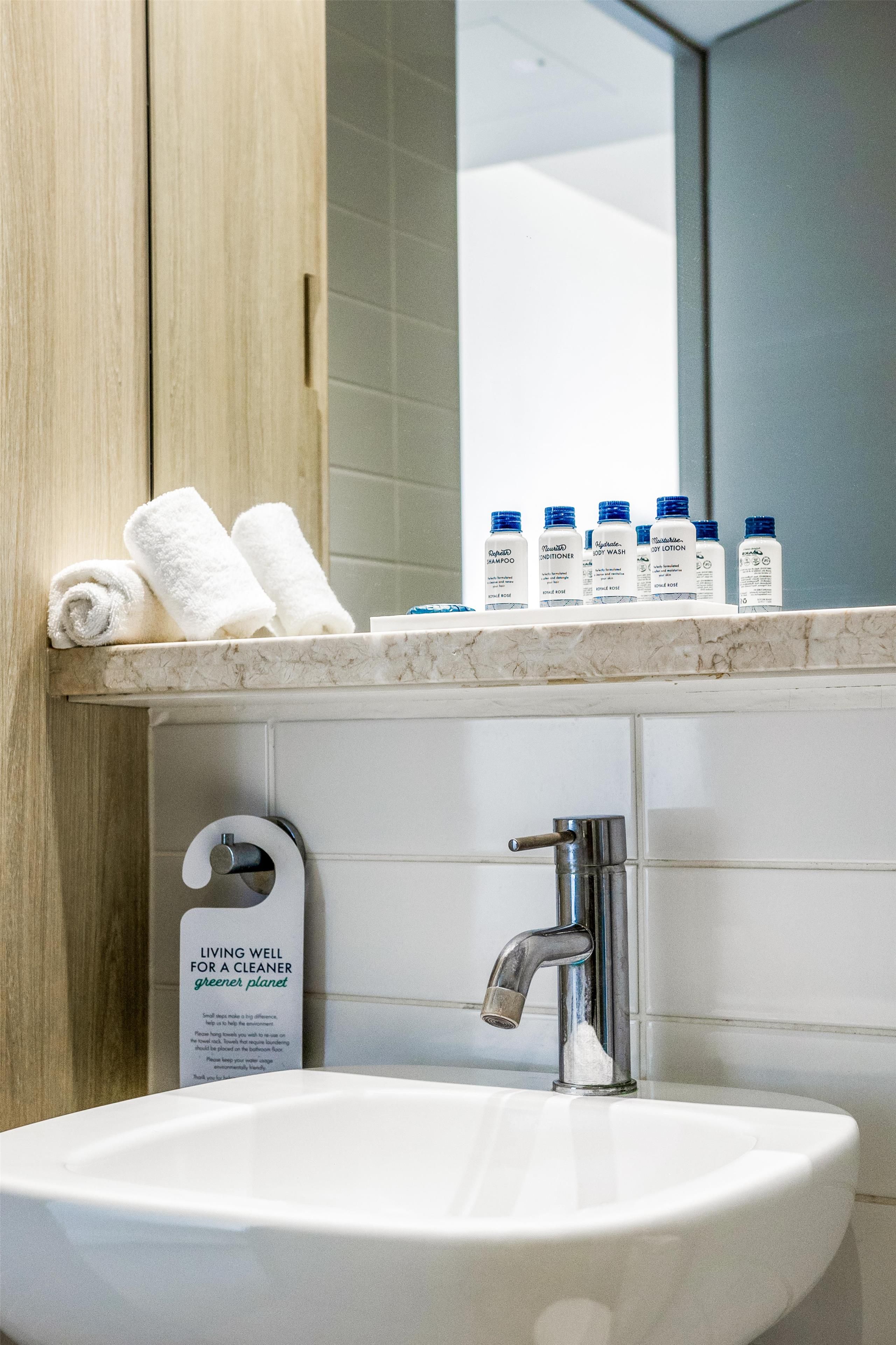 A bathroom with a sink, a mirror, and toiletries on the countertop.