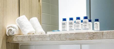 A bathroom with a sink, a mirror, and toiletries on the countertop.