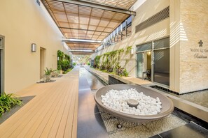 A corridor with a water feature, wooden flooring, and a wall with a sign. - Oaks Redcliffe Mon Komo Suites (Redcliffe)