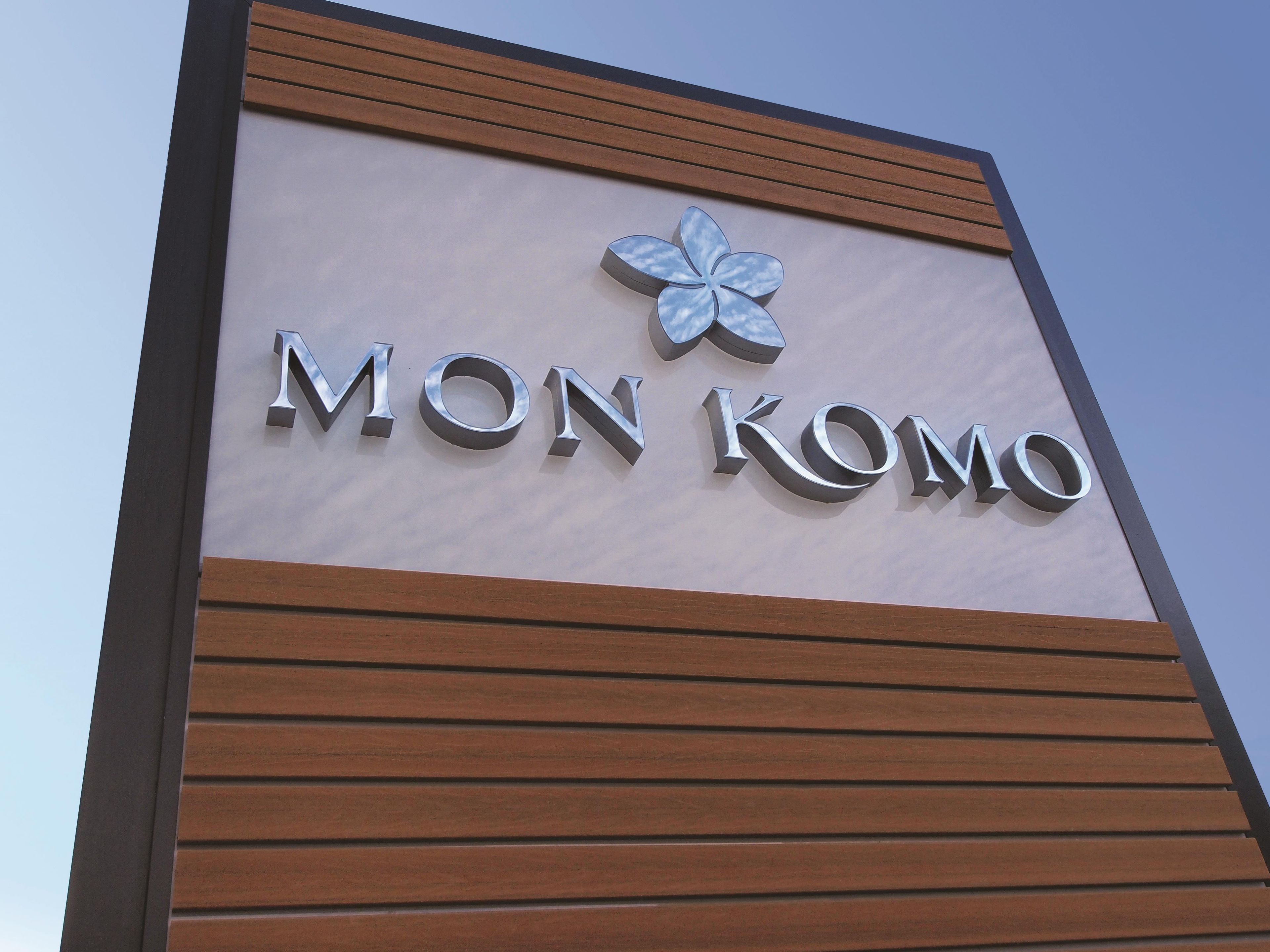 A sign with the name 'MON KOMO' and a stylized flower emblem.