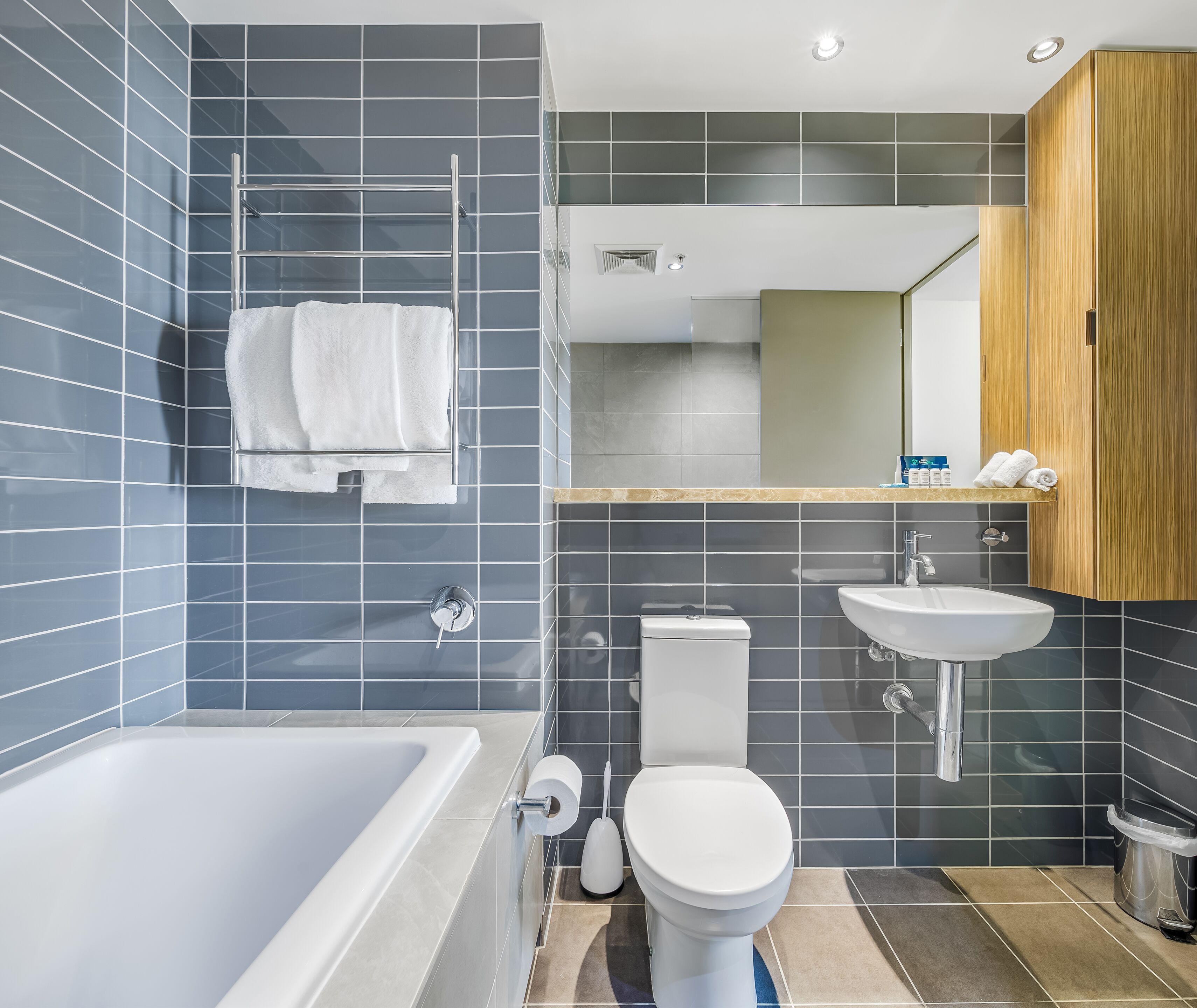 Une salle de bain moderne équipée d’une baignoire, de toilettes, d’un lavabo et d’un porte-serviettes.