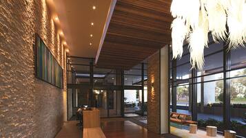 A modern lobby with a wooden reception desk, large windows, and a hanging light fixture.