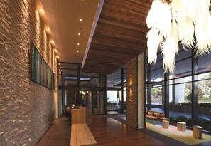 A modern lobby with a wooden reception desk, large windows, and a hanging light fixture. - Oaks Redcliffe Mon Komo Suites (Redcliffe)