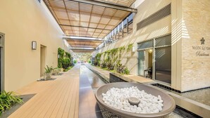 A corridor with a wooden ceiling, a water feature, and a building with a sign reading "MON KOMP".