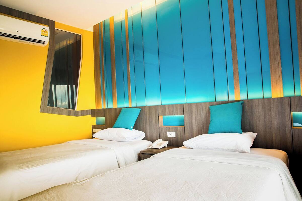 Une chambre d’hôtel avec deux lits, un grand miroir et un climatiseur fixé au mur.