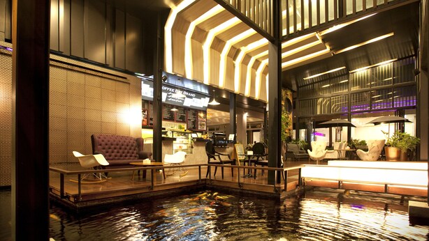 An indoor pool area with seating and a coffee shop in the background.
