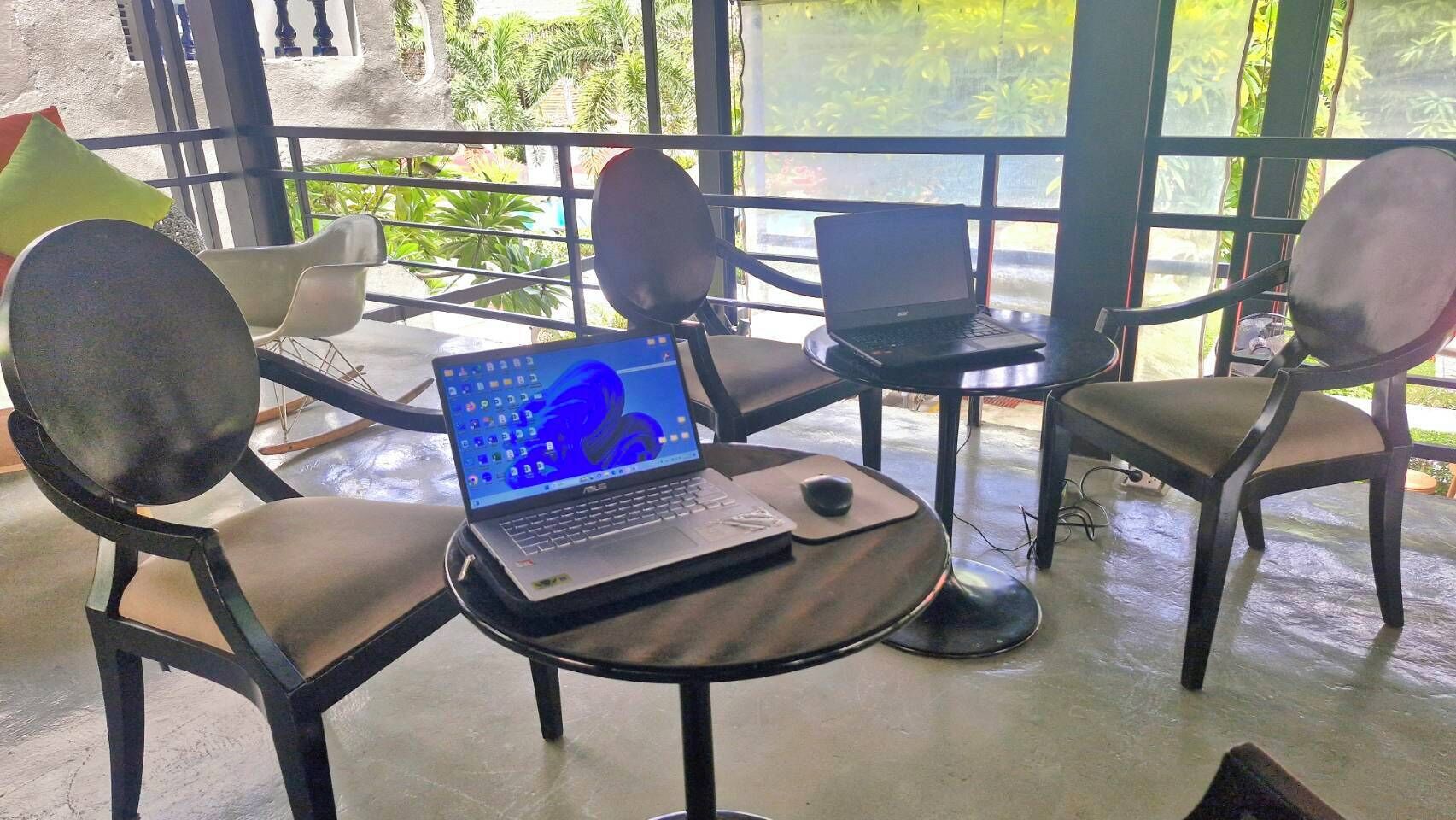 A seating area with four chairs and a table, each with a laptop on it.