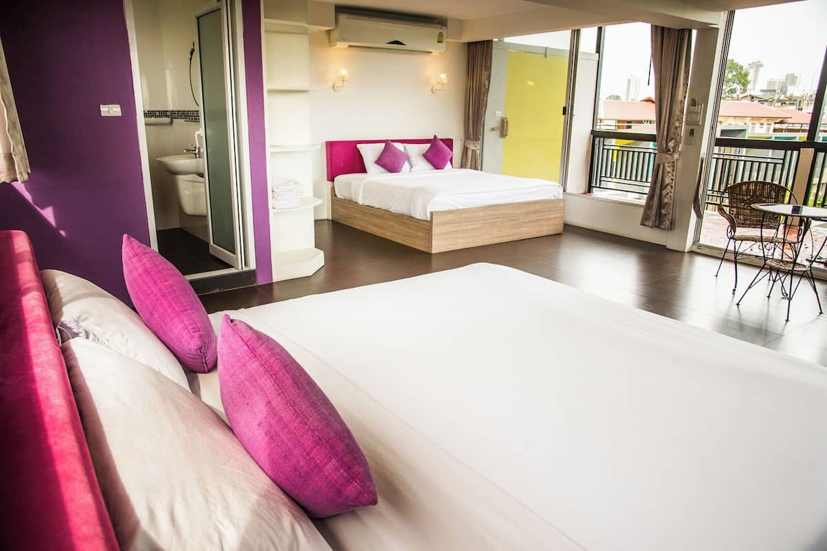Une chambre d’hôtel moderne avec un grand lit, un balcon avec une chaise et une vue sur la ville.