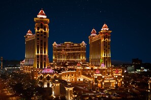 Un gran complejo hotelero iluminado durante la noche con múltiples torres y un edificio central.