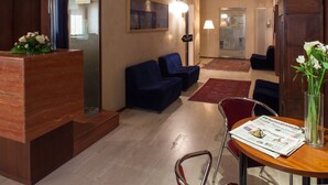 A modern hotel lobby with a reception desk, seating area, and a dining table with a menu.