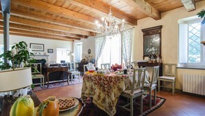 A spacious dining area with a wooden ceiling and a chandelier, a table set for a meal, and a view of the outdoors through a window. - B e B San Valentino (Osimo)