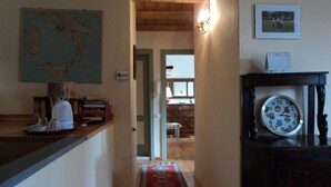 A hallway with a wooden floor, a red patterned rug, a clock, a map on the wall, and a framed photo above a table. - B e B San Valentino (Osimo)