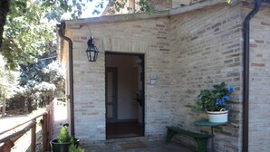 A brick building with a door, a bench, and potted plants. - B e B San Valentino (Osimo)