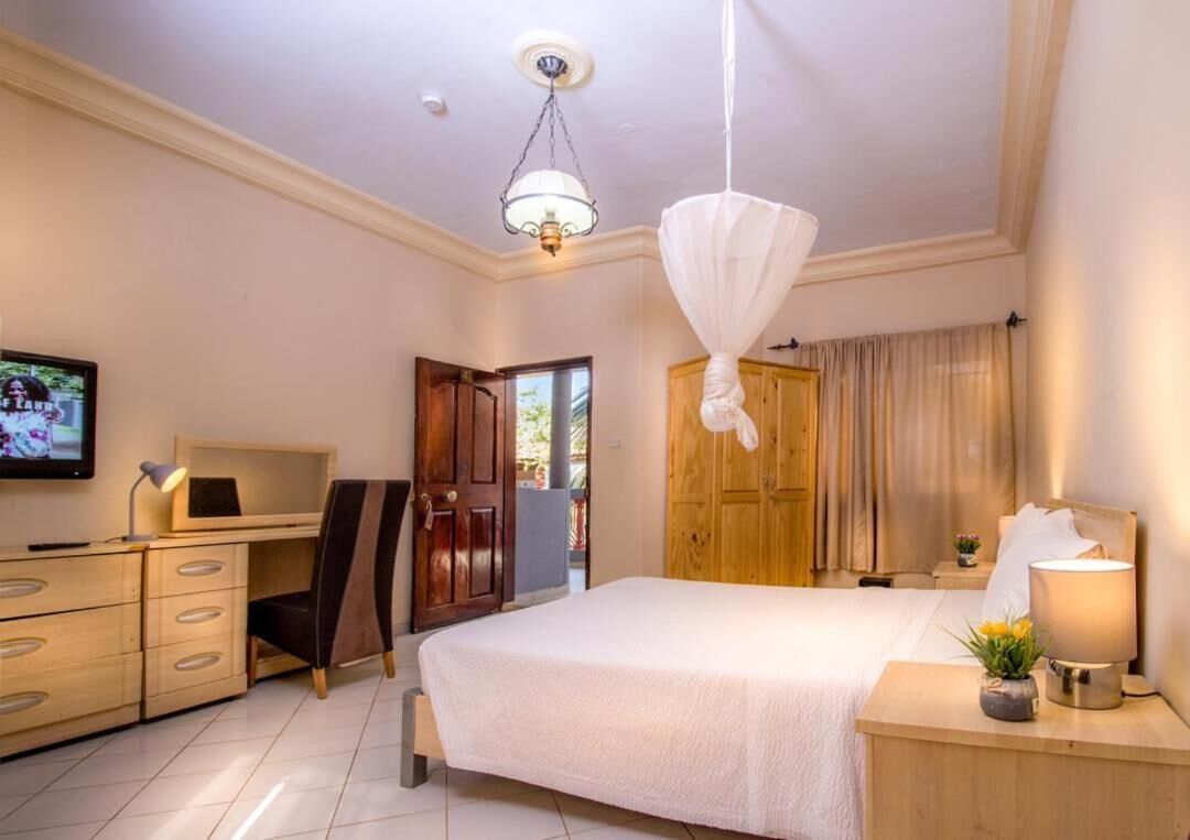 Un dormitorio con cama, escritorio, silla, televisor y armario.
