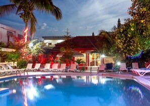 A swimming pool with lounge chairs, palm trees, and a building with red-tiled roof. - Seaview Gardens Hotel (Brufut)
