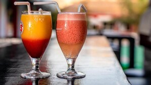 Zwei Cocktails mit Strohhalmen auf einer Bar.
