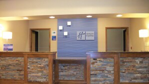 A reception area with a stone wall, two doors, and a sign for Holiday Inn Express. - Holiday Inn Express Cortland by IHG (Cortland)
