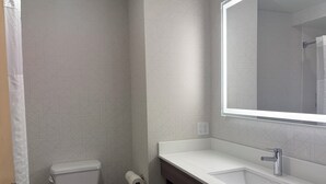 Un baño moderno con inodoro, lavamanos y espejo.