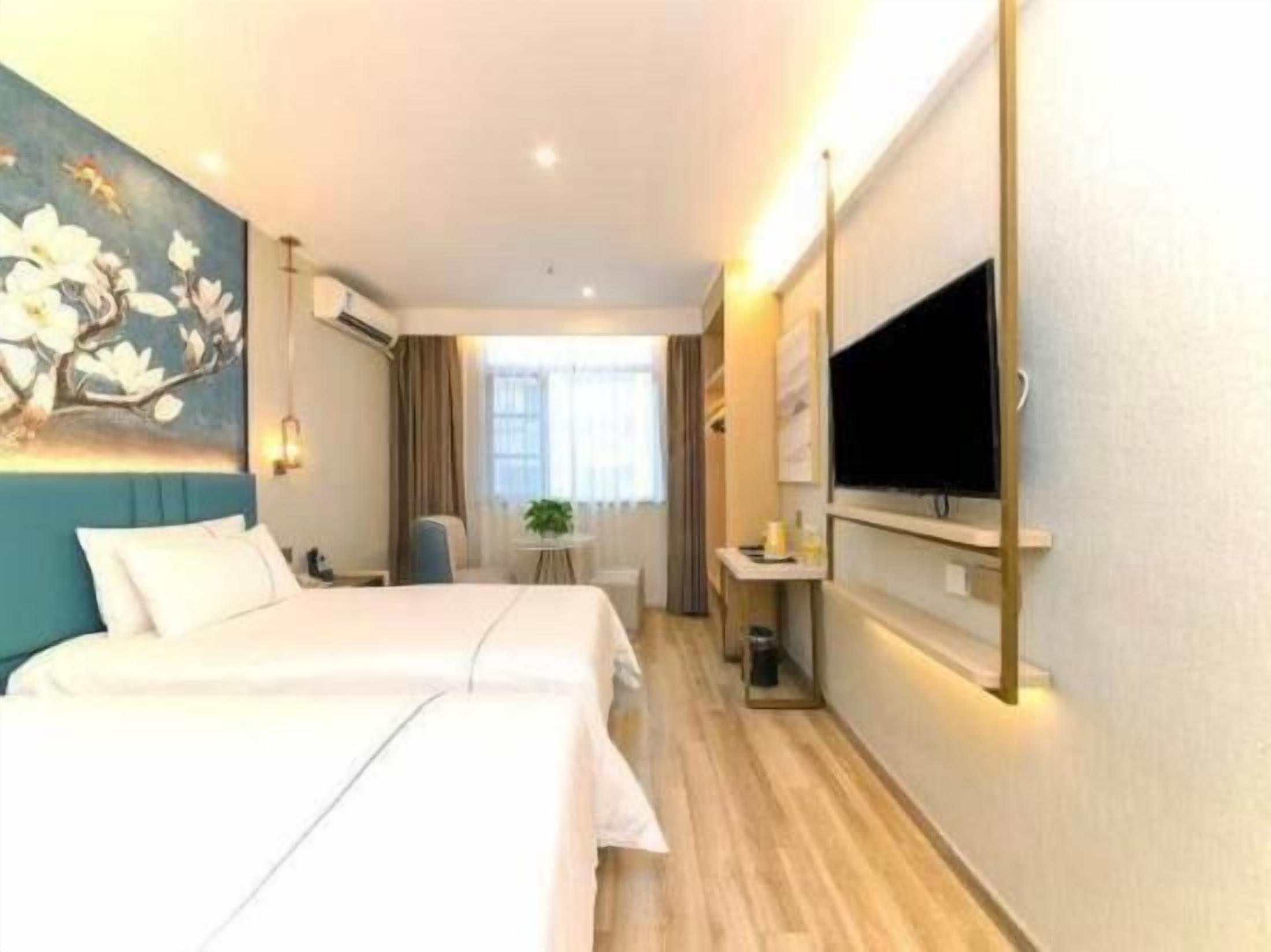 Een hotelkamer met twee bedden, een televisie, een tafeltje en een schilderij aan de muur.