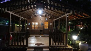 A wooden building with a covered entrance, a tiled floor, and a small garden area with a lamp post. - Resort Primo Bom Terra Verde (Baga)