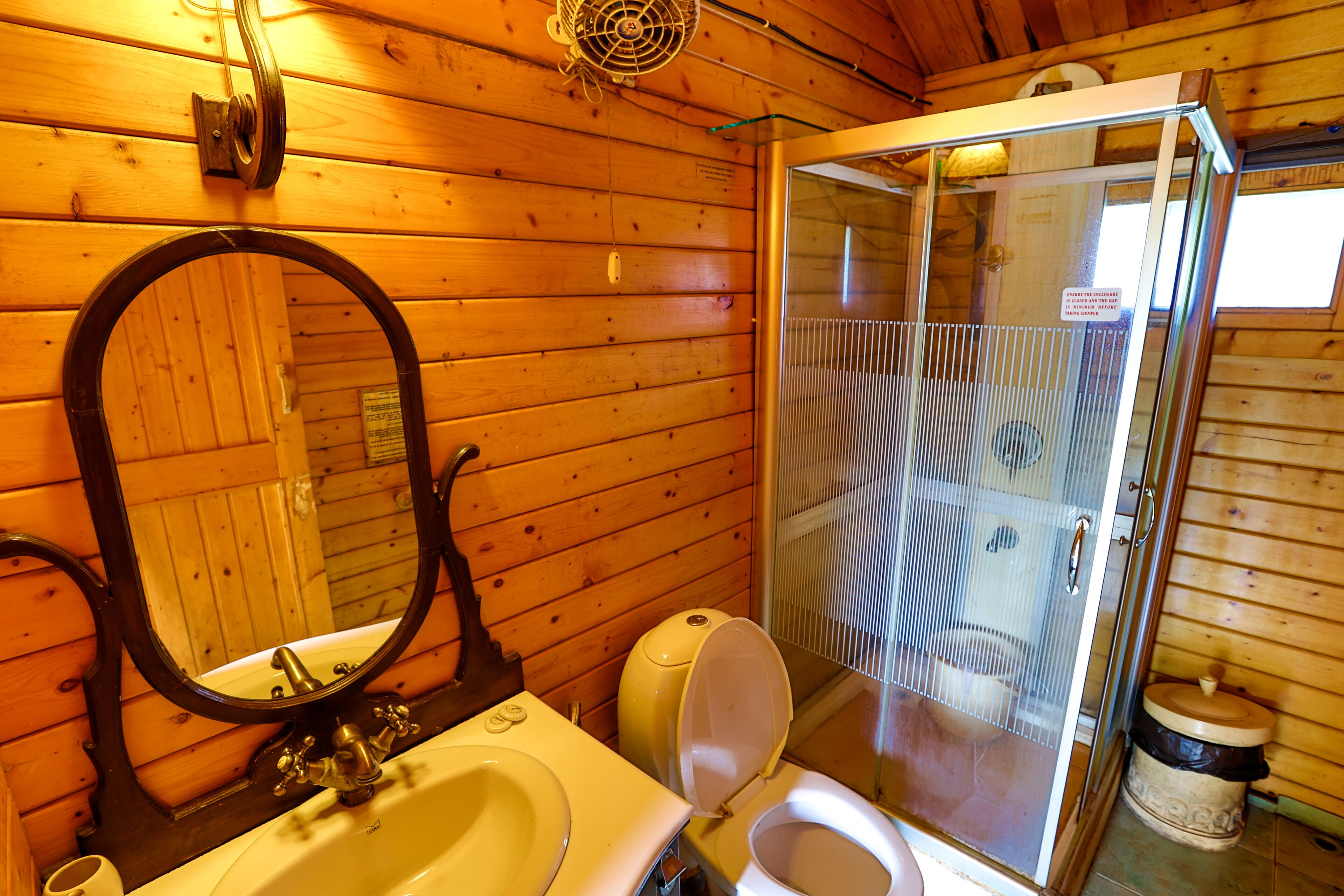 A wooden cabin bathroom with a sink, toilet, and shower.