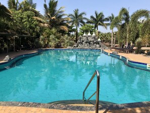 Una piscina al aire libre, sombrillas, sillones reclinables de piscina