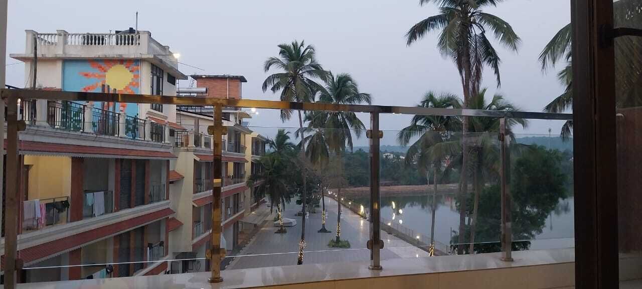 Vista desde un balcón sobre una calle con palmeras y una masa de agua.