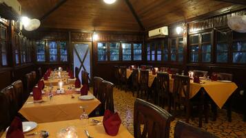 A restaurant with wooden interiors, multiple tables set for dining, and large windows.