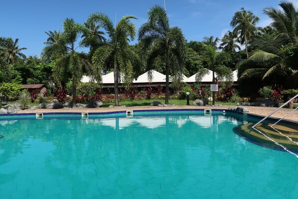 Alberca al aire libre, sombrillas en la alberca y camastros 