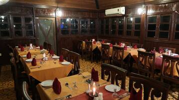 Un restaurante con paneles de madera, varias mesas dispuestas con servilletas rojas, platos y cubiertos.