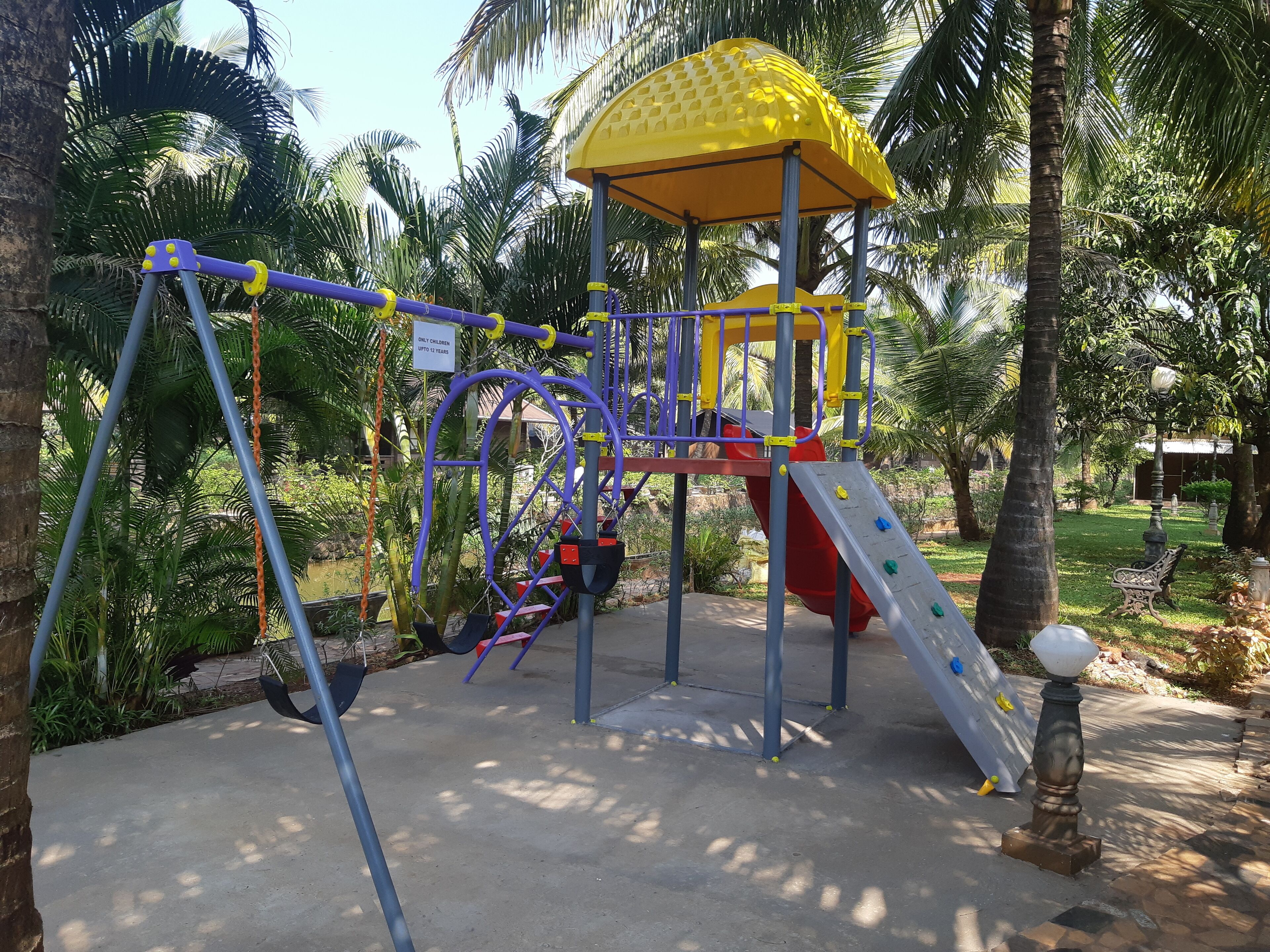 A playground with a yellow climbing dome, a red slide, and a purple swing set.