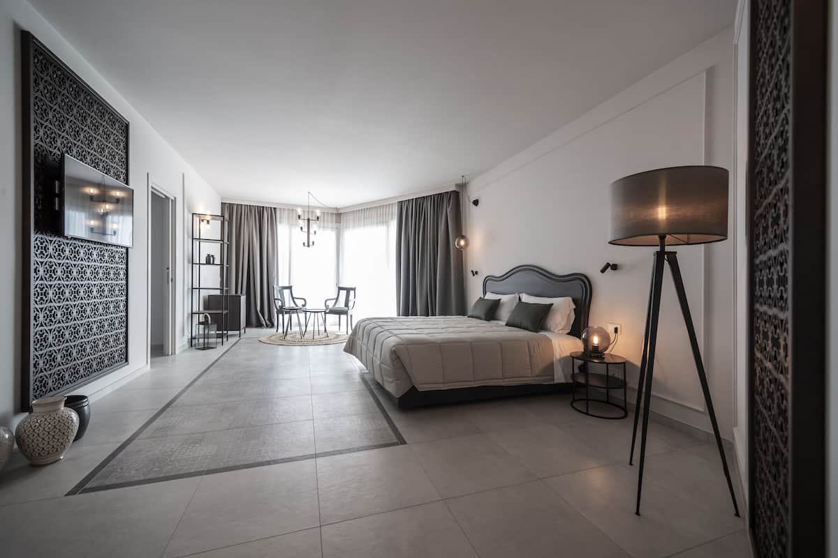 Ein modernes Schlafzimmer mit Bett, Nachttischlampe und Blick auf einen Essbereich.