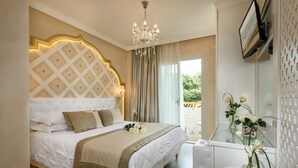 A hotel room with a large bed, a chandelier, a glass partition, and a view of greenery outside. - Luxor e Cairo The Beach Resort (Jesolo)