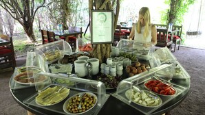 A buffet setup with various food items in clear containers, surrounded by wooden tables and chairs. - Hemerans Anatolia Otel (Kemer)