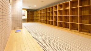 A spacious room with tiled walls and a wooden floor, featuring a large wooden shelving unit along one wall. - Shiga Lake Hotel (Yamanouchi)