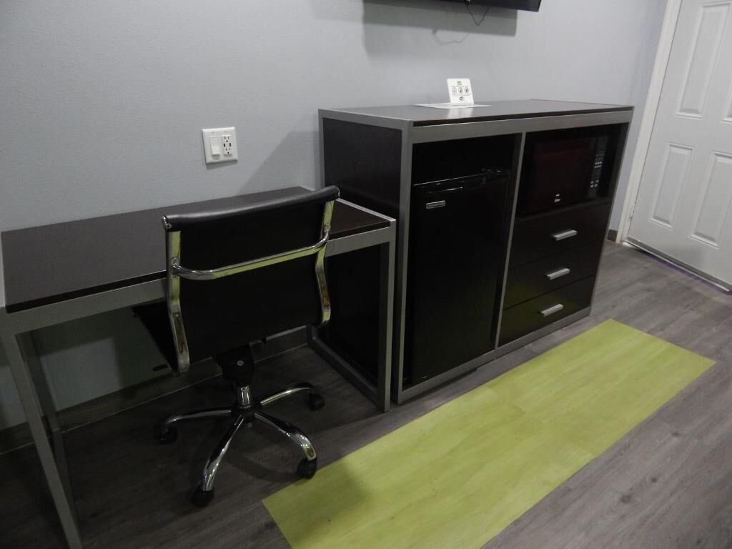 Een kamer met een bureau, stoel en een kast met lades.