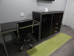 Una habitación con escritorio, silla y una cómoda con cajones.