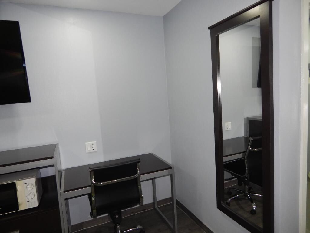 A small, modern room with a desk, chair, and a large mirror.