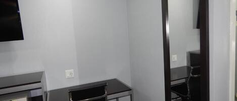 A small, modern room with a desk, chair, and a large mirror.
