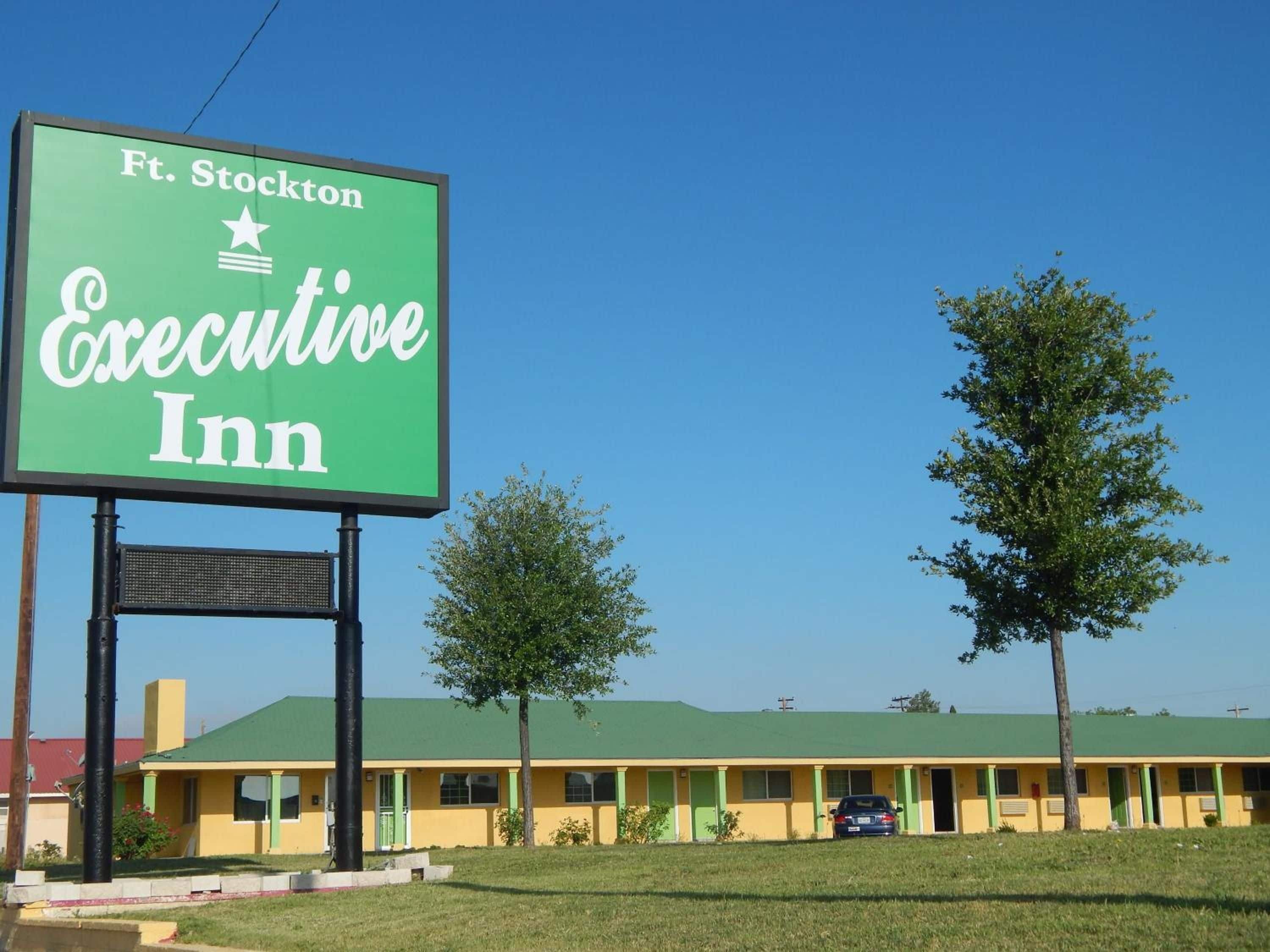A motel with a green signboard, a yellow building, and a car parked in front.