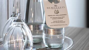 Una botella de agua del hotel Bernstein, un vaso y una bandeja de metal sobre una superficie de madera.