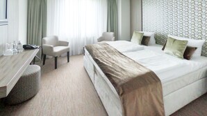 A hotel room with a bed, two chairs, a desk, and a window with curtains. - Bernstein B&B (Stassfurt)