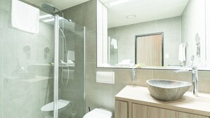 A modern bathroom with a glass-enclosed shower, a large mirror, and a wooden vanity with a stone basin. - Bernstein B&B (Stassfurt)