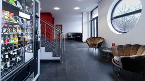 A modern lobby with a vending machine, a staircase, and seating area. - Bernstein B&B (Stassfurt)