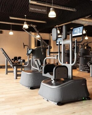 Un gimnasio con equipo de ejercicio, que incluye una cinta de correr y máquinas de pesas.