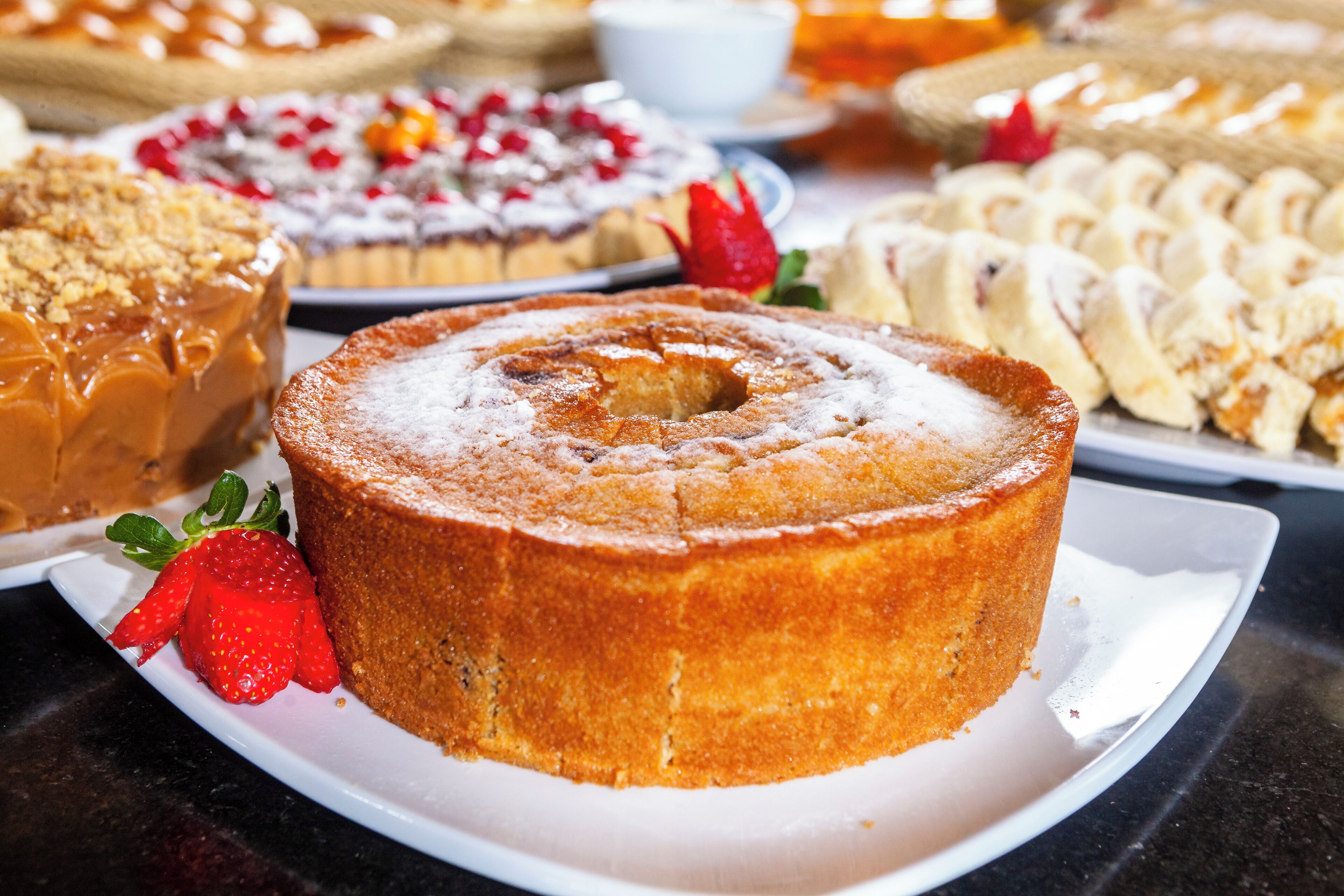 Une variété de desserts sont disposés sur une table, dont un gâteau en forme de couronne garni de fraises.