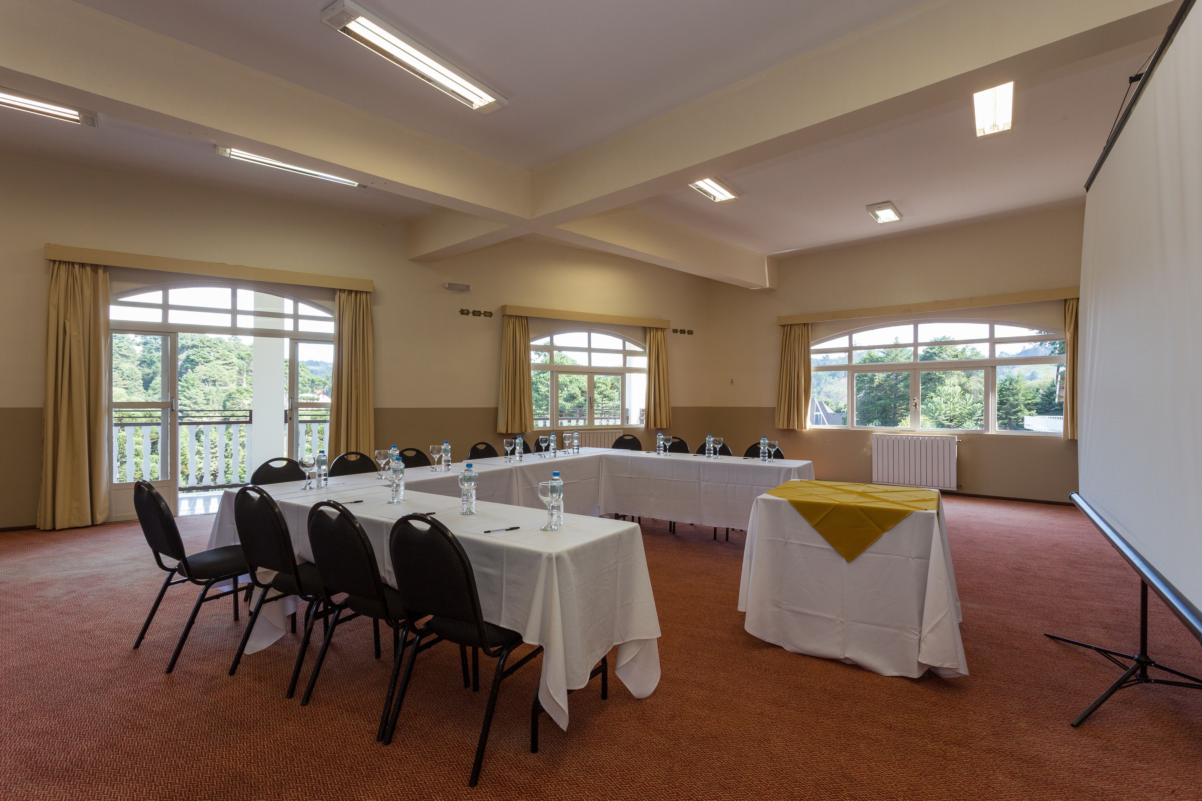 Uma sala de conferências com uma mesa comprida, cadeiras e um projetor.