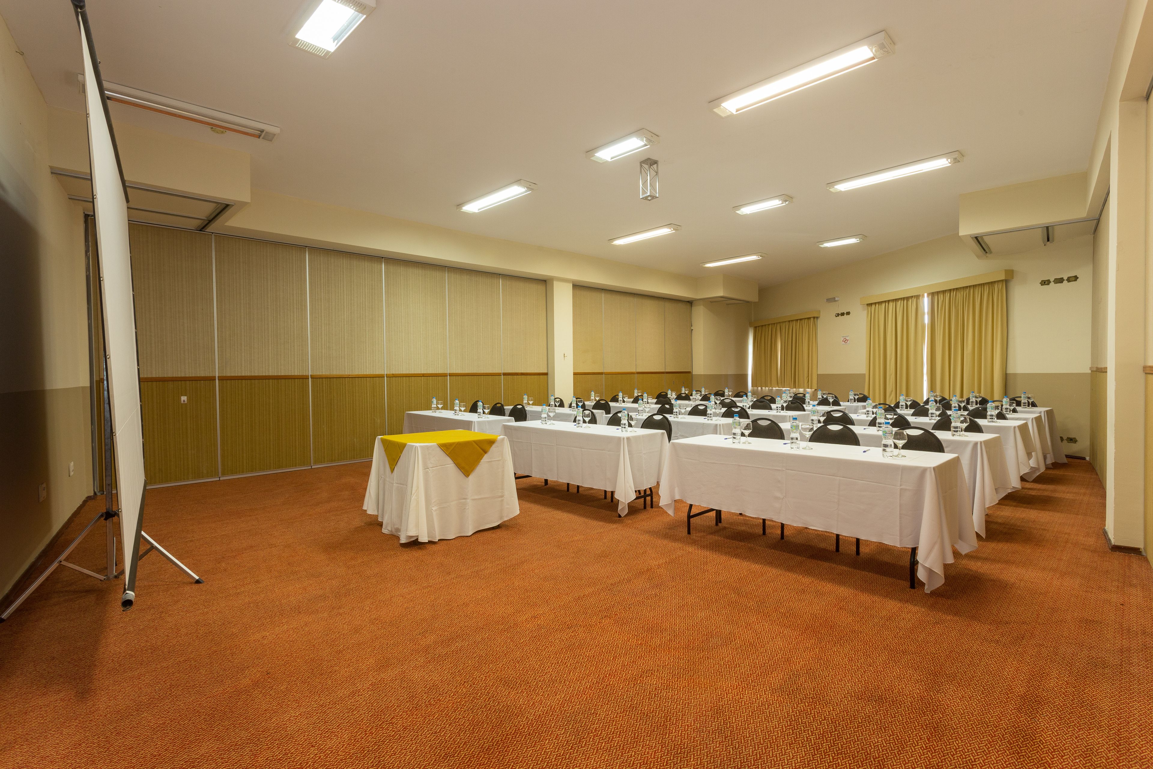 Ein Konferenzraum mit mehreren Tischen, Stühlen und einer Tafel.