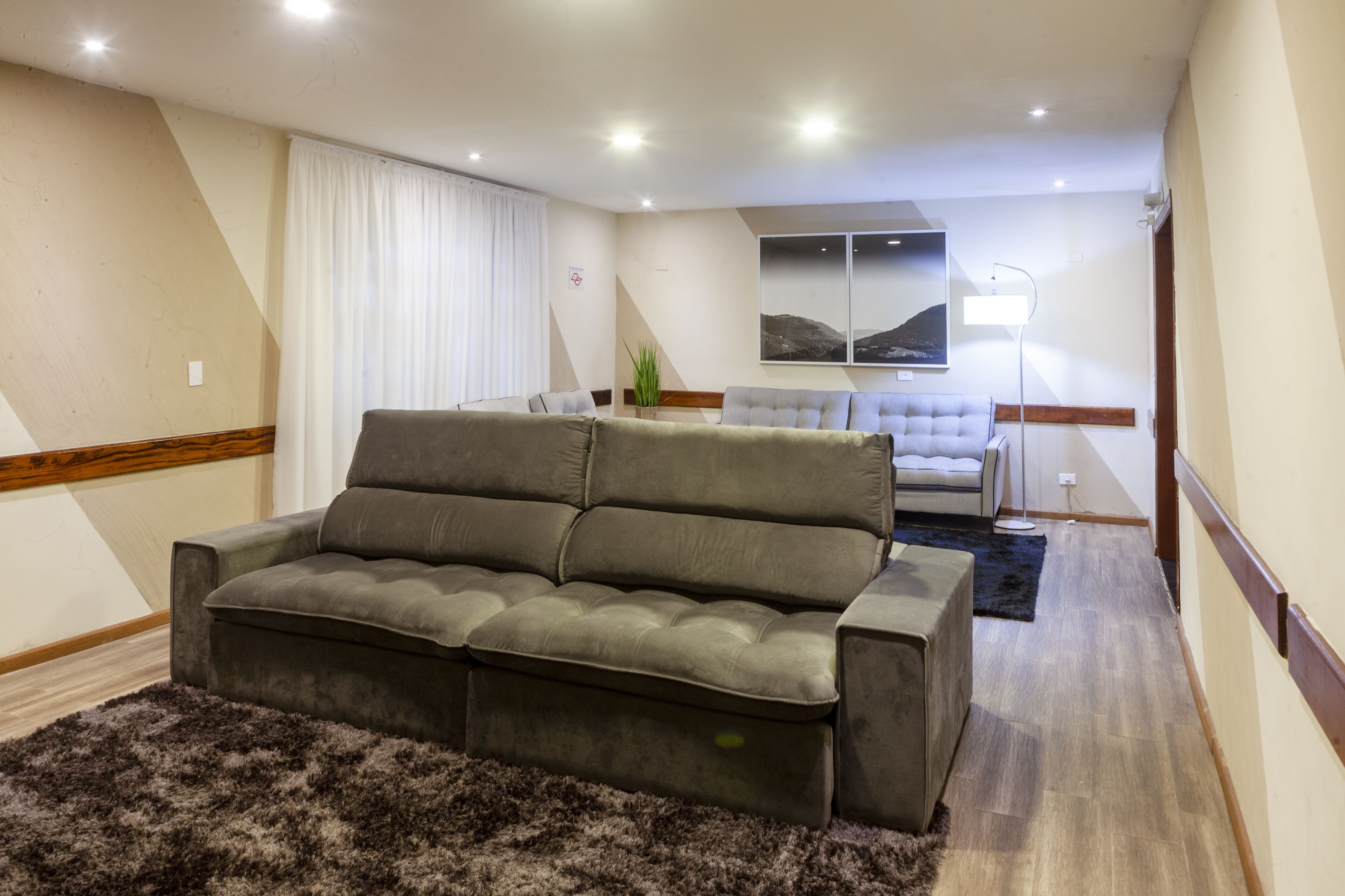 A living room with a grey sofa, a white armchair, a black rug, and a wooden floor.
