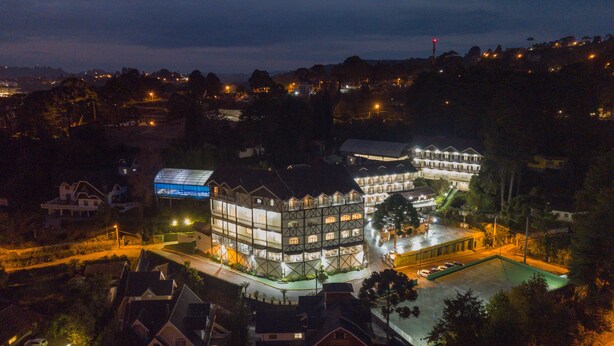 A large, multi-story hotel with a prominent glass facade and a swimming pool. - Hotel Leão da Montanha (Campos do Jordão)